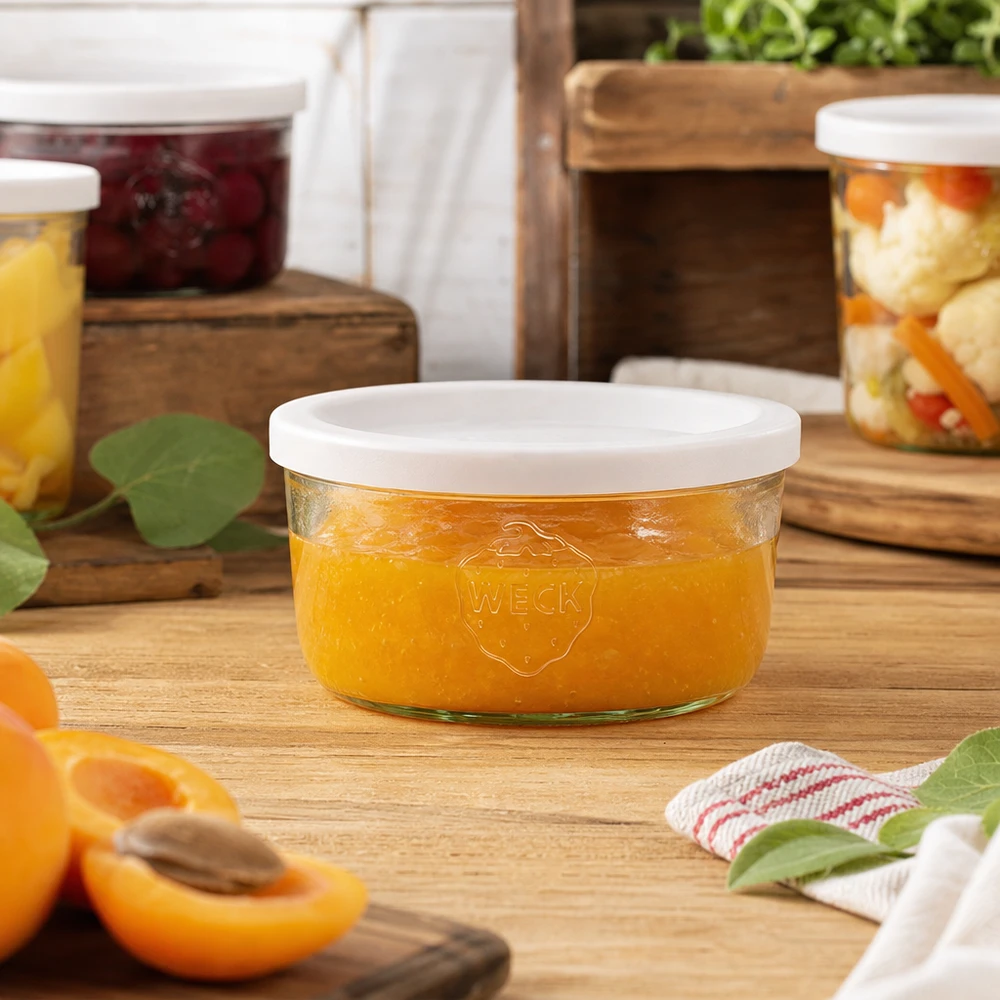 WECK Pot renversé de 165ml rempli de confiture orange dans un environnement de cuisine naturel avec des bocaux en arrière-plan