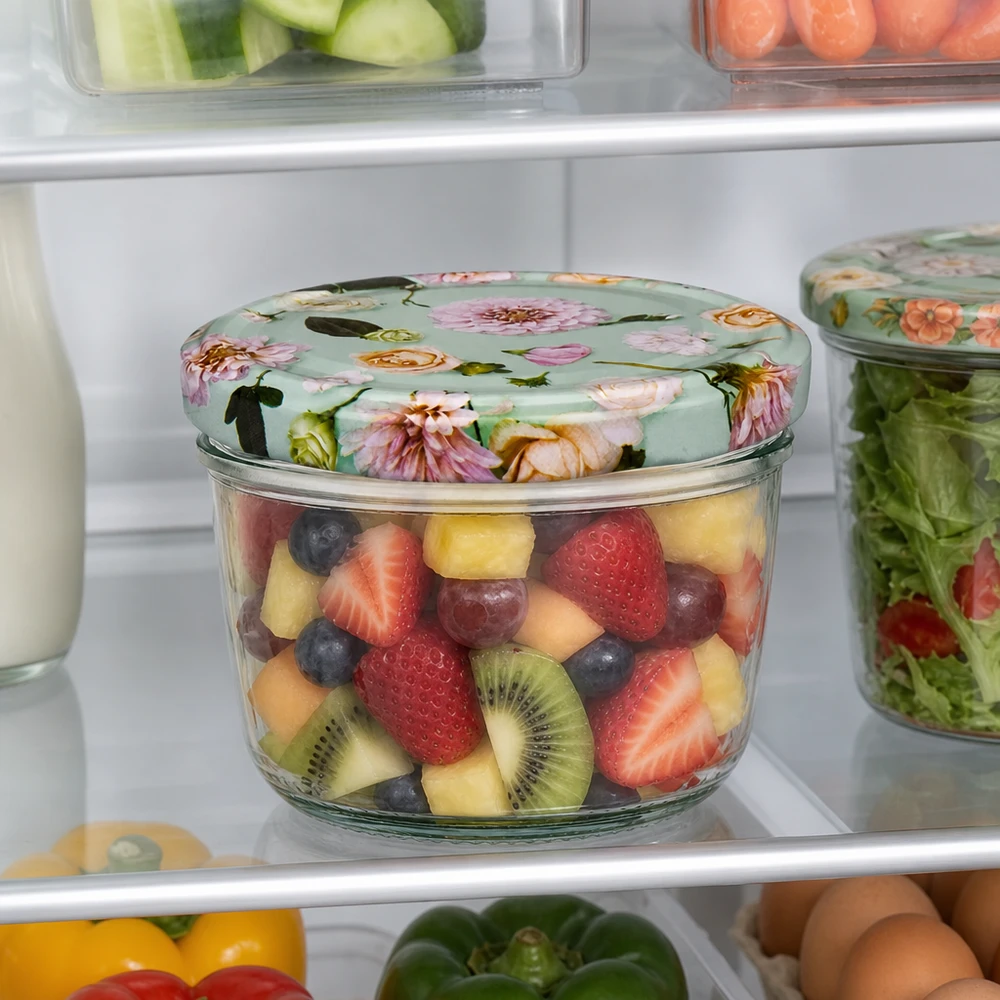 Verres de 230 ml + couvercle BasicSeal fleur menthe UNiTWIST Pot renversé de 230 ml avec couvercle BasicSeal fleur menthe rempli de salade de fruits au réfrigérateur à côté d'autres récipients de stockage