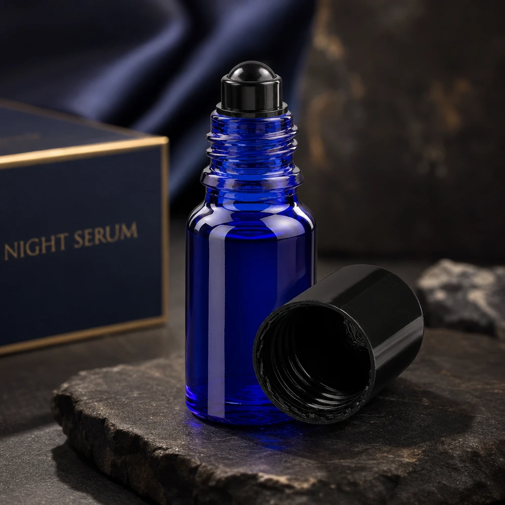 Flacon en verre bleu cobalt à bille de 10 ml avec une bille noire, présenté dans un emballage luxueux pour sérum de nuit