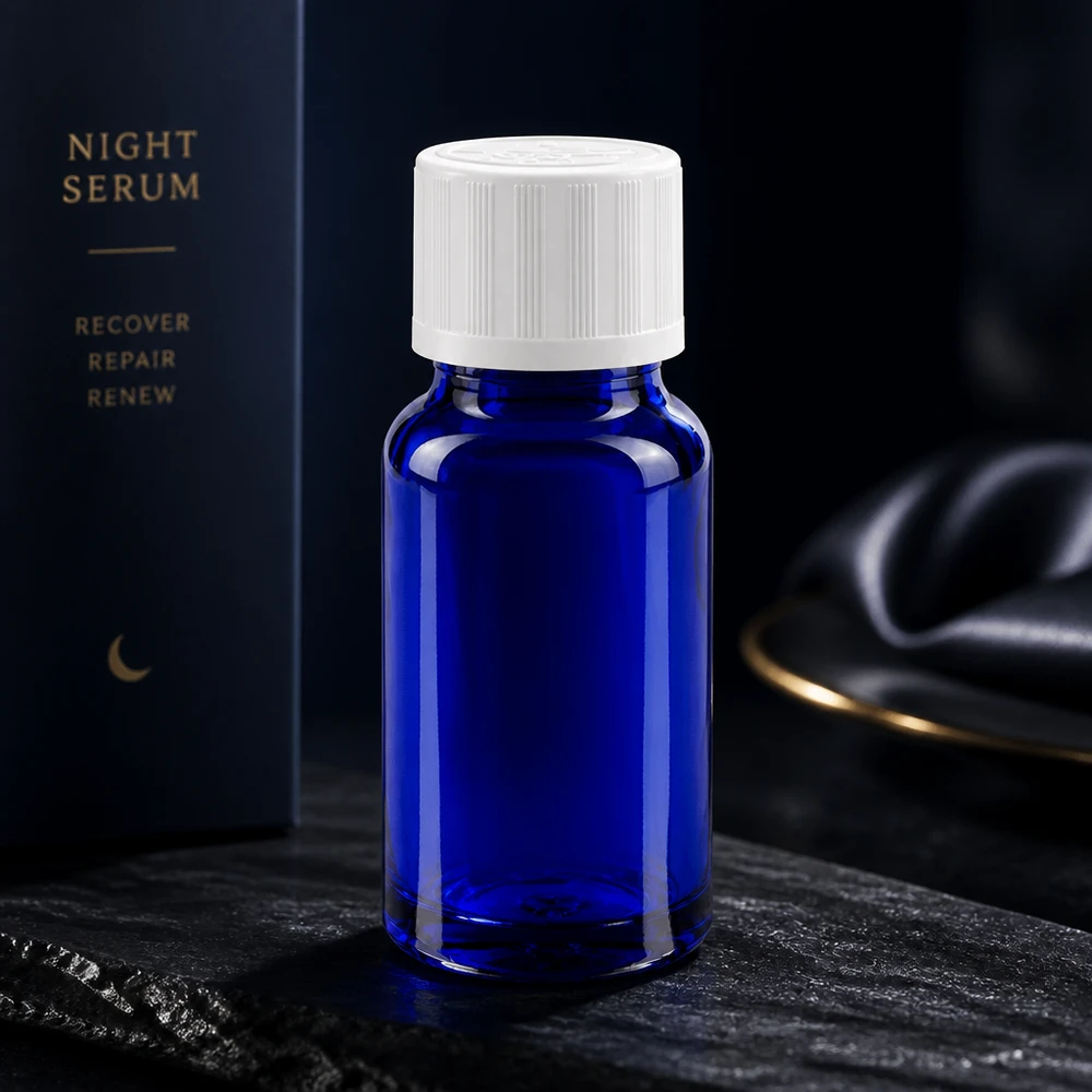 Flacon en verre bleu cobalt de 10 ml avec bouchon de sécurité blanc, posé sur une pierre d'ardoise foncée