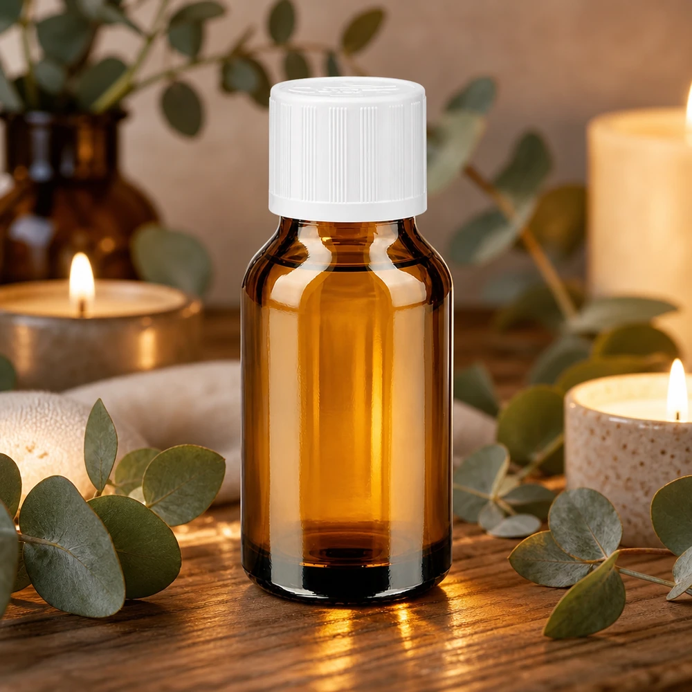 Petit flacon en verre ambré de 30 ml muni d'un bouchon de sécurité blanc, entouré de branches d'eucalyptus et de bougies