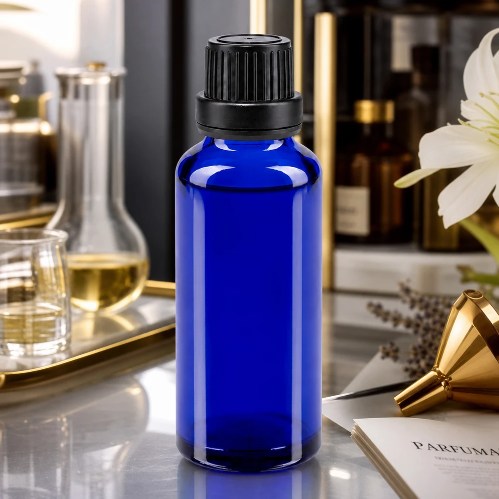 Flacon en verre bleu cobalt de 30 ml avec un bouchon noir strié, posé sur une élégante table en marbre