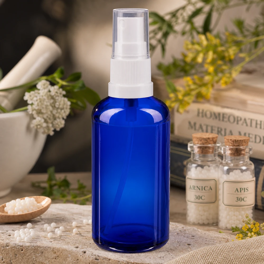 Flacon de pharmacie bleu 50ml embout spray blanc Flacon pulvérisateur en verre d'apothicaire bleu de 50 ml muni d'une pompe blanche, à côté de granules homéopathiques