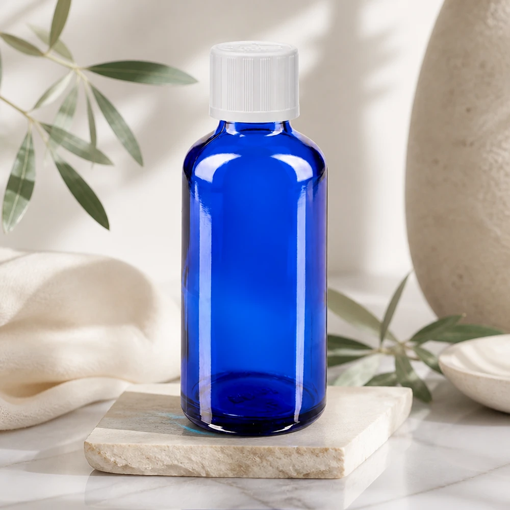 Flacon de pharmacie bleu cobalt de 50 ml muni d'un bouchon compte-gouttes à sécurité enfant, sur fond couleur crème