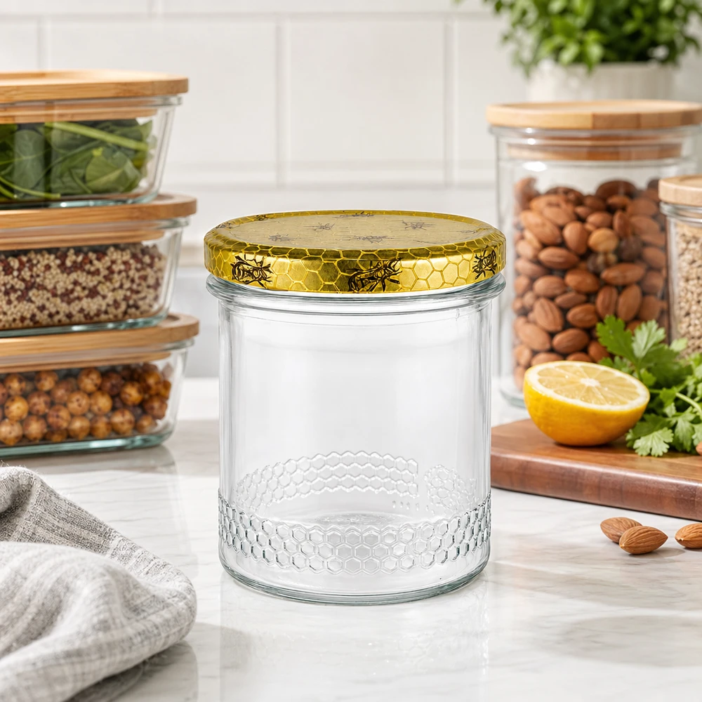 Pot de miel de 400 ml avec couvercle doré en nid d'abeille sur le plan de travail de la cuisine, bocaux à provisions avec des noix en arrière-plan